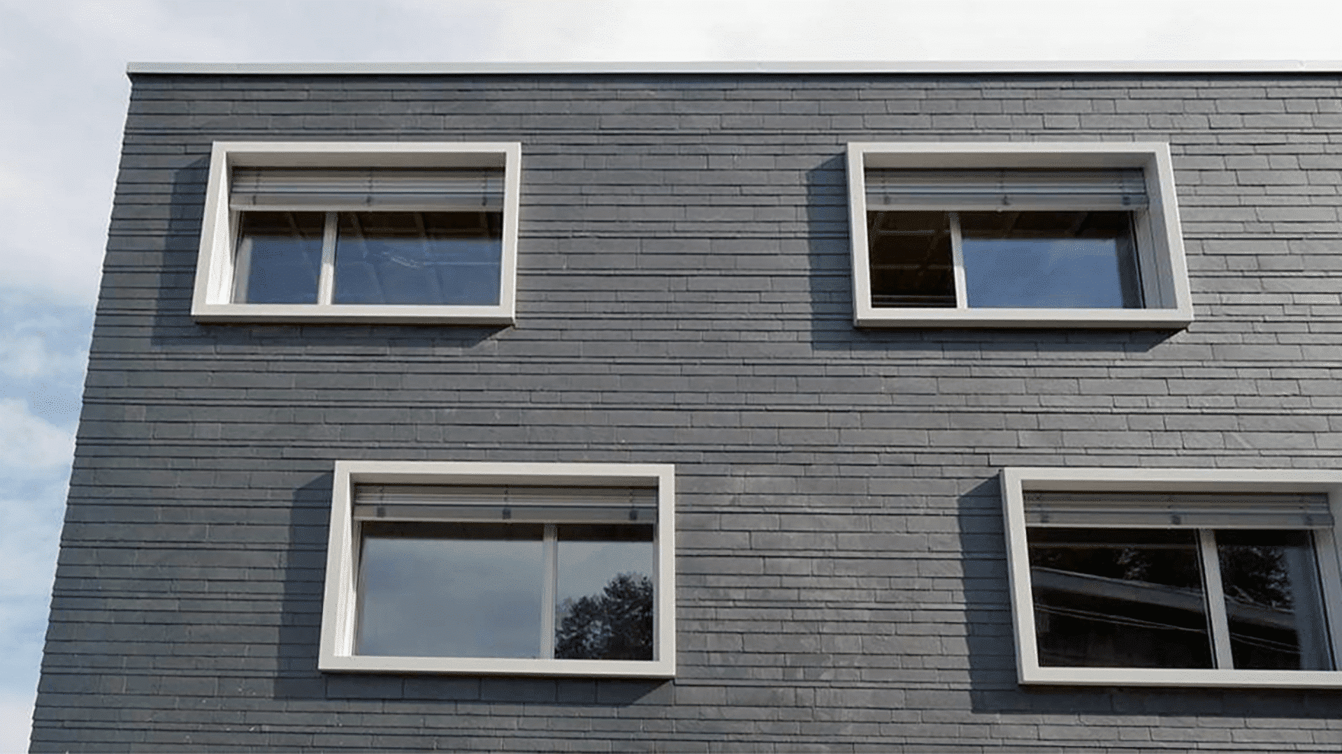 Modernes Haus mit Fensterzargen als Stilelement und grauer Fassade