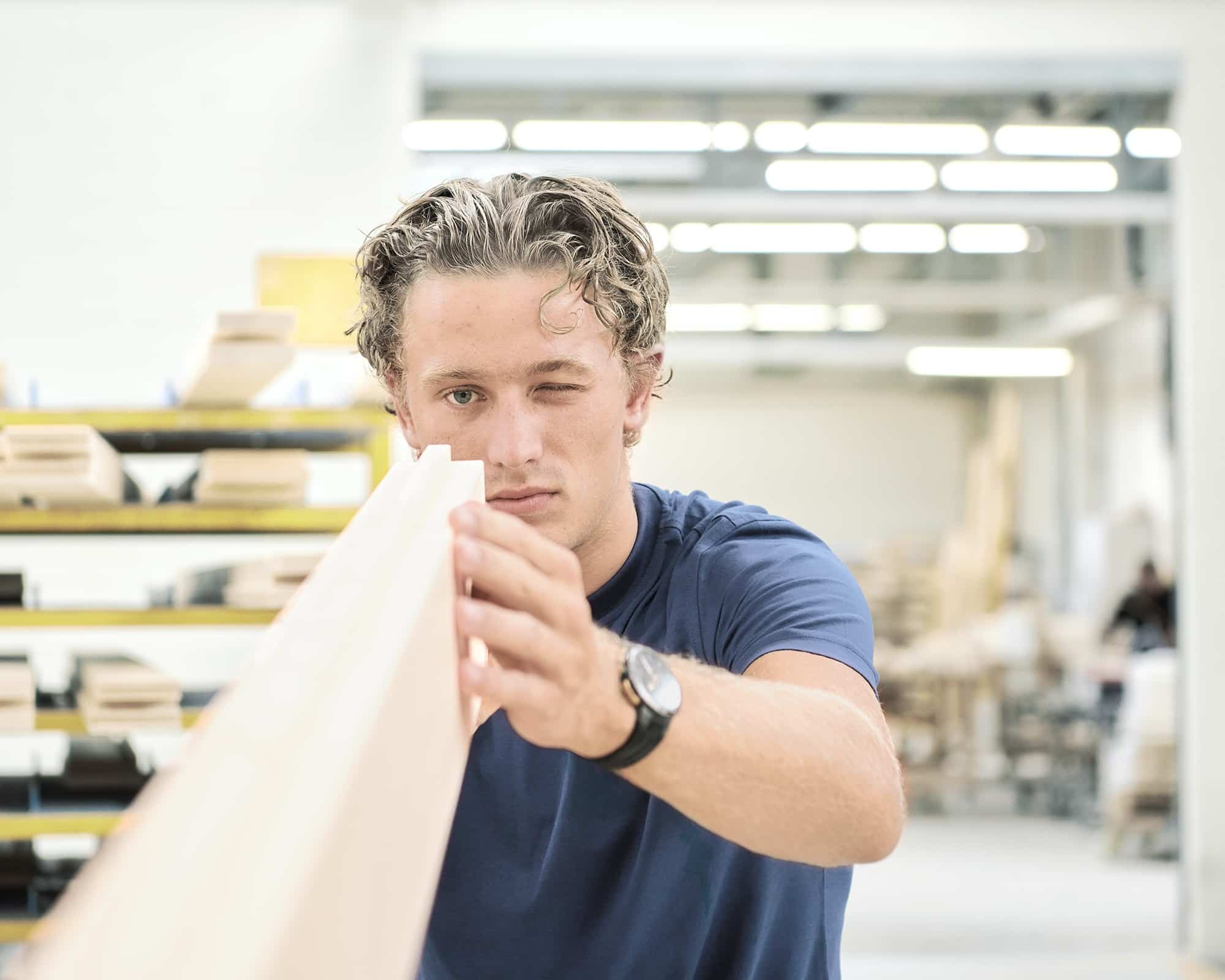 Auszubildender Schreiner prüft Holzqualität