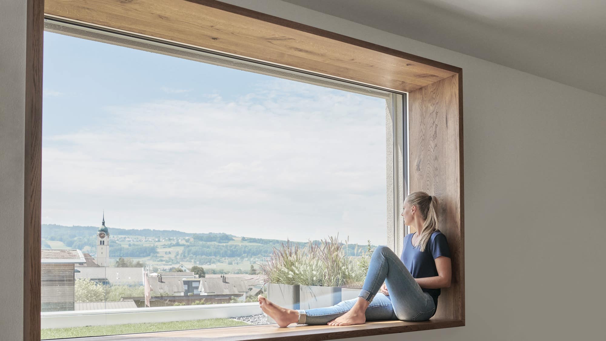 Frau sitzt auf der Fensterbank und schaut aus dem Fenster