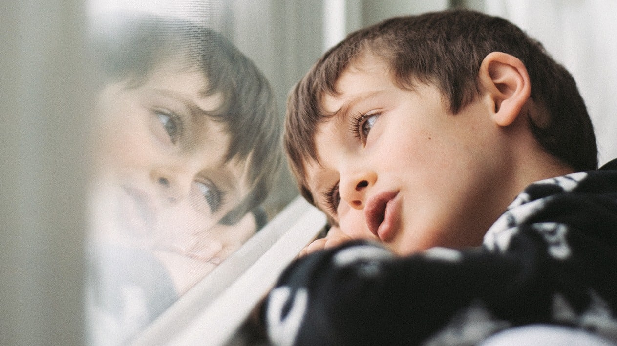 Kleiner Junge blickt verträumt aus Fenster