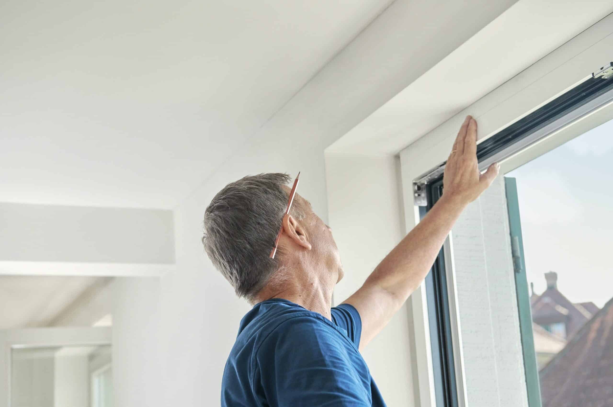 Mann mit blauem T-Shirt prüft das neue Fenster auf den Qualitätsstandard