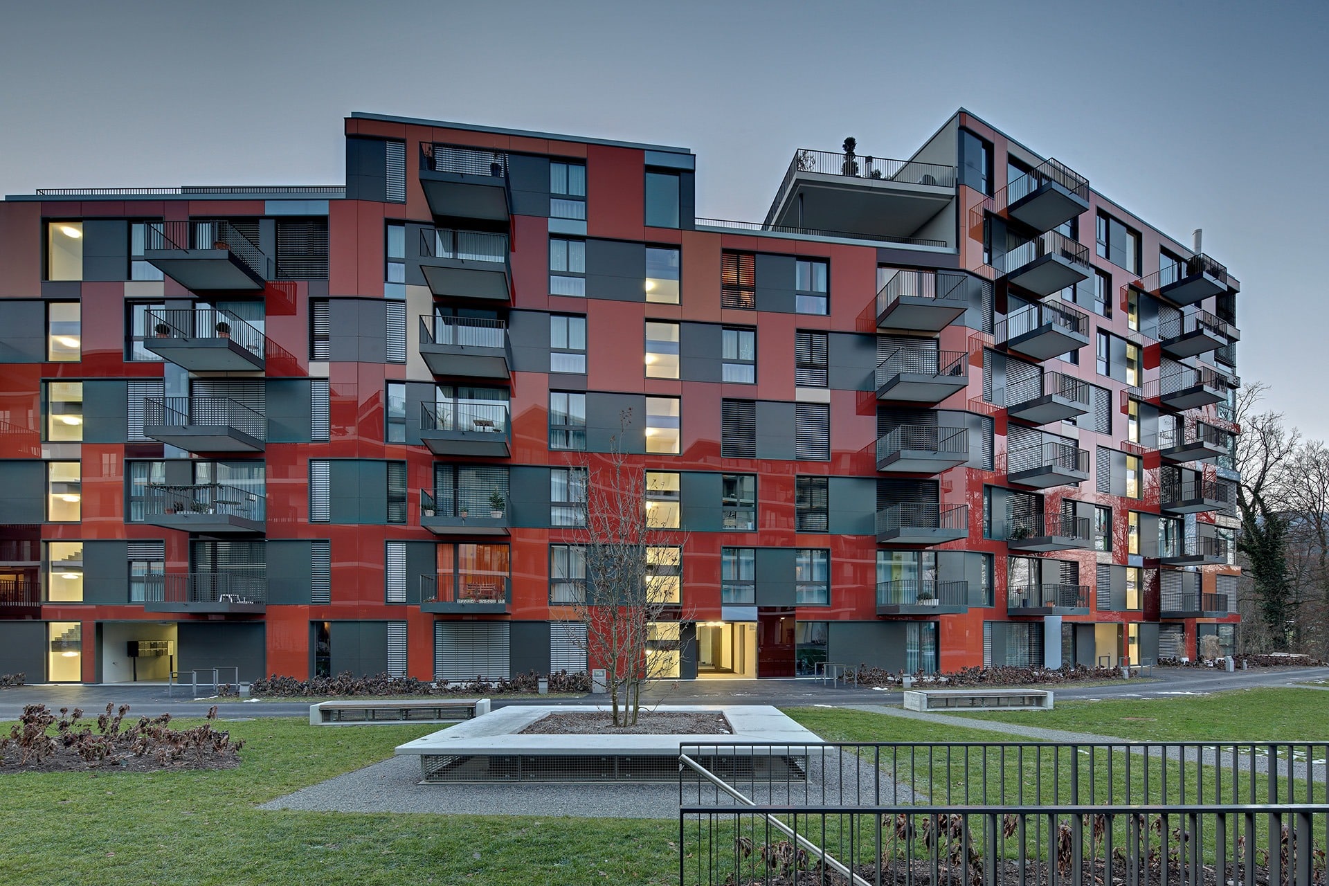 Fenster Neubau Wohnsiedlung Adliswil Aussenansicht, rote Fassade bei Dämmerung