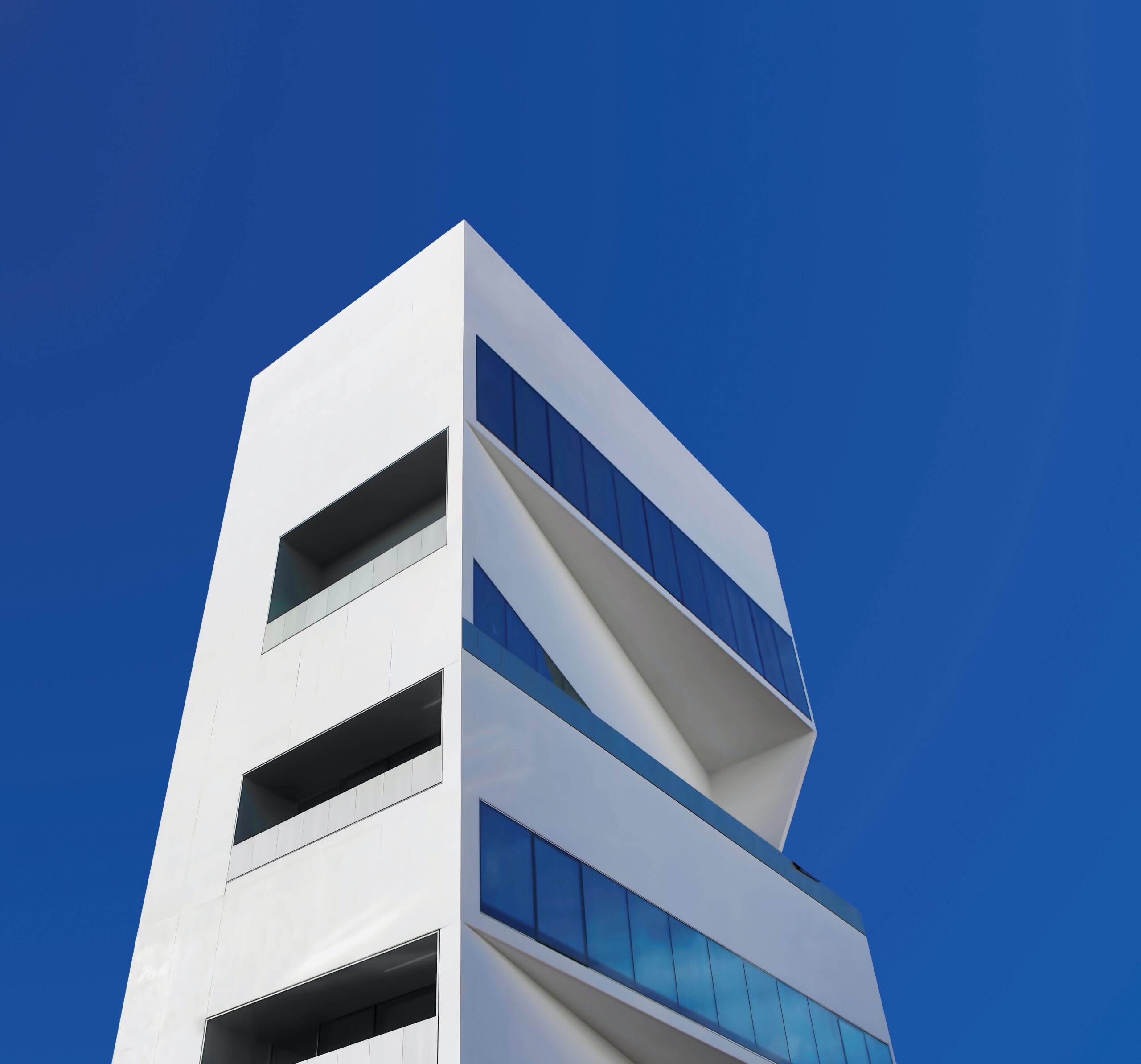 Weisses Hochhaus mit grossen Fenster und blauem Himmel