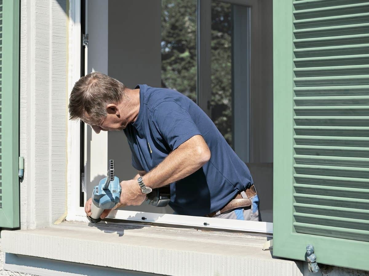 Ein Blick in die Glaskugel der Baubranche: Ein Monteur in einem blauen T-Shirt renoviert das Fenster