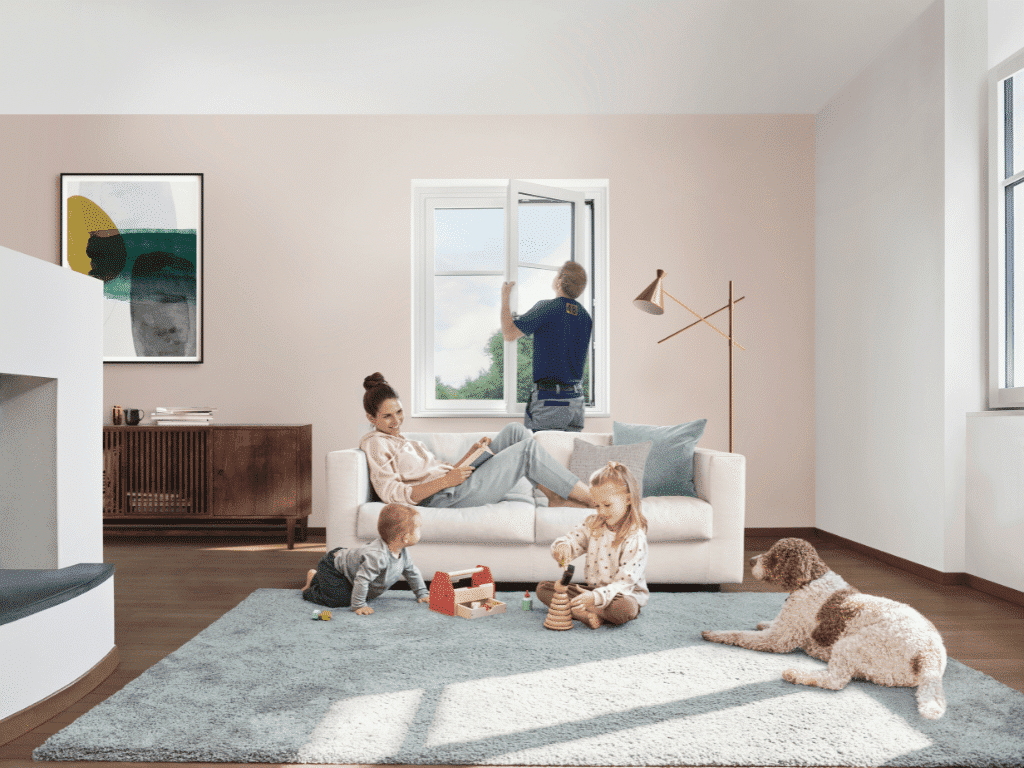 Frau liegt auf dem Sofa und Kinder spielen im Vordergrund während Monteur das Renovationsfenster einbaut
